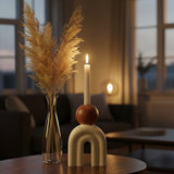 Cream arch-shaped candle holder with rounded brown detail and a tall lit taper candle