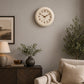 Cream colour wall clock above sofa with neutral cushions and plant