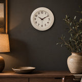 Cream wall clock above wooden side table with plant and decor