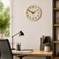 Cream plastic wall clock above home office desk with black lamp and plant