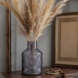 Dark grey textured glass vase with tall dried pampas grass displayed on a wooden table