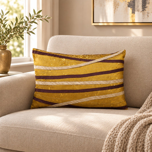Gold and brown striped decorative cushion with curved metallic detailing on a neutral sofa