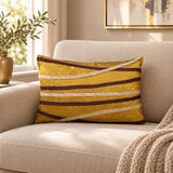 Gold and brown striped decorative cushion with curved metallic detailing on a neutral sofa