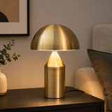 Gold finish table lamp with dome shade on dark side table
