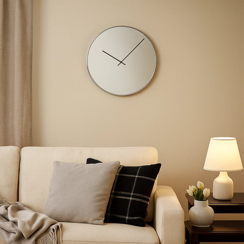 Gold mirrored wall clock above sofa with cushions and table lamp