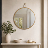 Gold round wall mirror above bathroom shelf with small plant