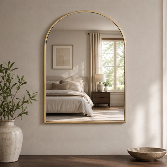 Gold wall mirror above vanity shelf in warm bathroom setting