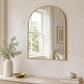 Gold arched wall mirror above bathroom sink with neutral decor