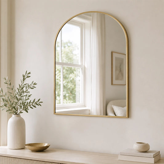 Gold arched wall mirror above bathroom sink with neutral decor