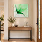 Green floral glass wall art with an abstract leaf design styled above a wooden hallway console