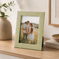 Green photo frame with textured border displayed on wooden shelf