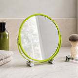 Green round shaving mirror on bathroom counter with plant reflection