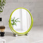 Green shaving mirror with feet on bathroom counter beside toiletries