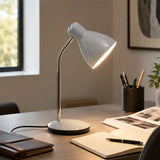 Grey desk lamp on office table with notebook, pens and books