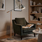 Grey floor lamp beside green armchair in modern lounge setting