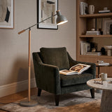 Grey floor lamp beside green armchair in modern lounge setting