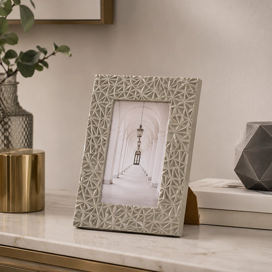 Grey decorative photo frame with patterned design on white surface