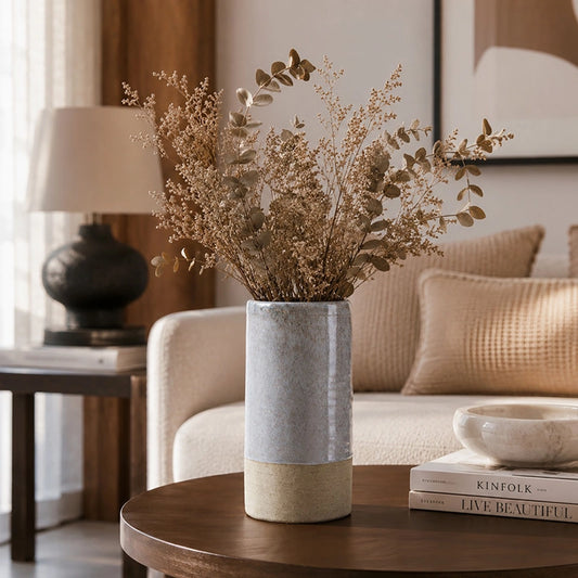 Grey textured decorative vase with dried foliage styled on a wooden side table