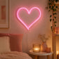 Pink heart LED neon light on bedroom wall beside bedside table with candles and plant