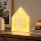 Home sweet home LED light box glowing on wooden sideboard beside vase and candles