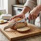 Stainless steel serrated bread knife cutting a sourdough loaf on a wooden chopping board