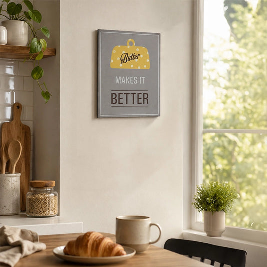 Wooden kitchen wall plaque with “Butter Makes It Better” quote displayed beside a dining table
