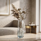 Large blue glass vase with dried foliage and decorative branches in a neutral living room