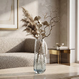 Large blue glass vase with dried foliage and decorative branches in a neutral living room