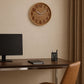 Brown round wall clock above home office desk with monitor