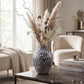 Large dark grey ceramic vase with textured pattern and tall dried botanical arrangement