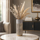Large grey and gold cylindrical vase with pampas grass and dried foliage on a round table