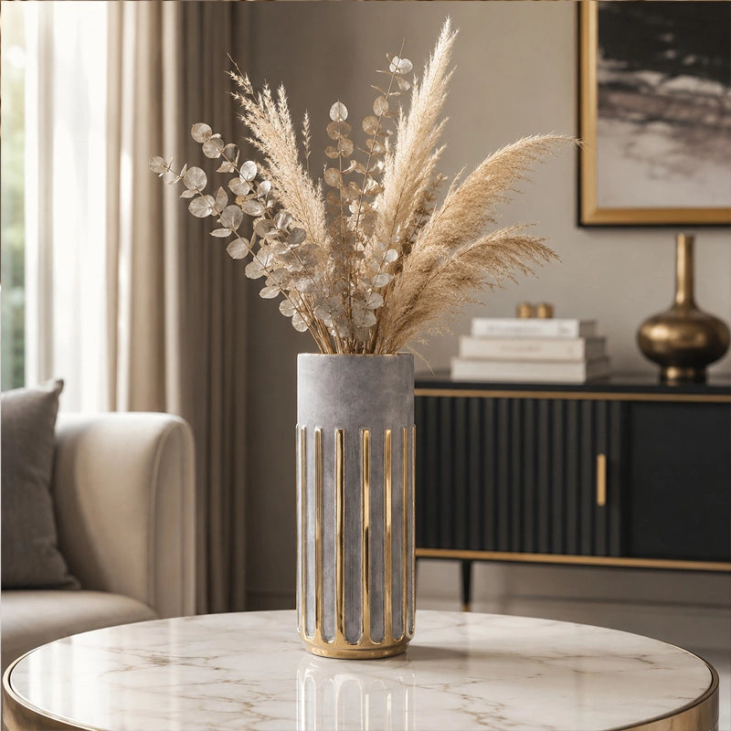 Large grey and gold cylindrical vase with pampas grass and dried foliage on a round table