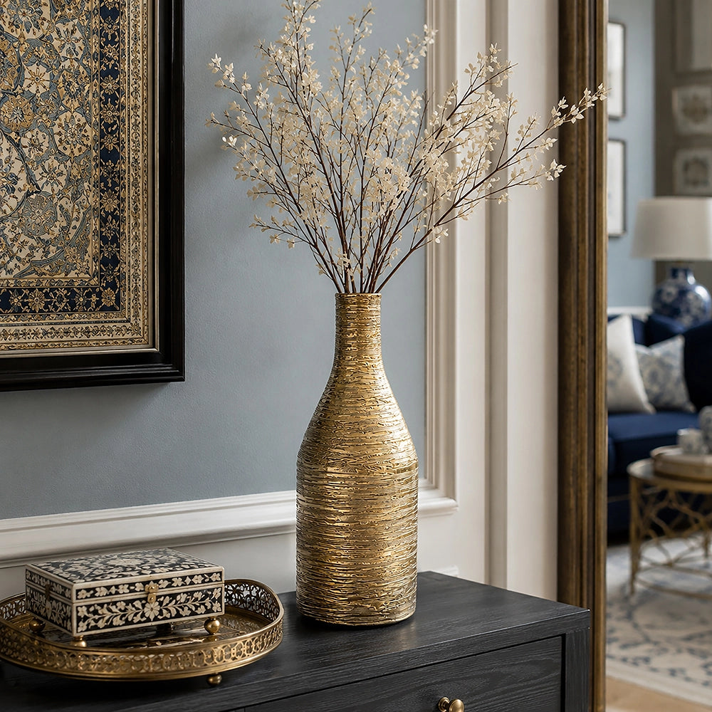 Large gold textured ceramic vase with delicate decorative branches displayed on a dark console table