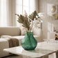 Large green textured glass vase with decorative dried stems styled on a marble coffee table