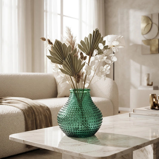 Large green textured glass vase with decorative dried stems styled on a marble coffee table