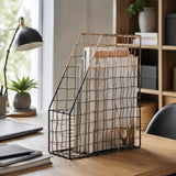 Black wire magazine file holder on wooden desk with notebooks