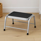 Silver metal step stool with black non-slip platform on wooden floor