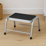 Silver metal step stool with black non-slip platform on wooden floor