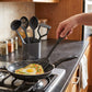 Nylon Kitchen Utensils Set of 5 with black spatula cooking fried egg in non-stick pan on gas stove