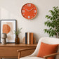Orange wall clock with large white numbers above wooden sideboard