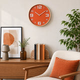 Orange wall clock with large white numbers above wooden sideboard
