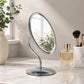 Silver oval swivel mirror on vanity table with makeup brushes