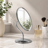 Silver oval swivel mirror on vanity table with makeup brushes