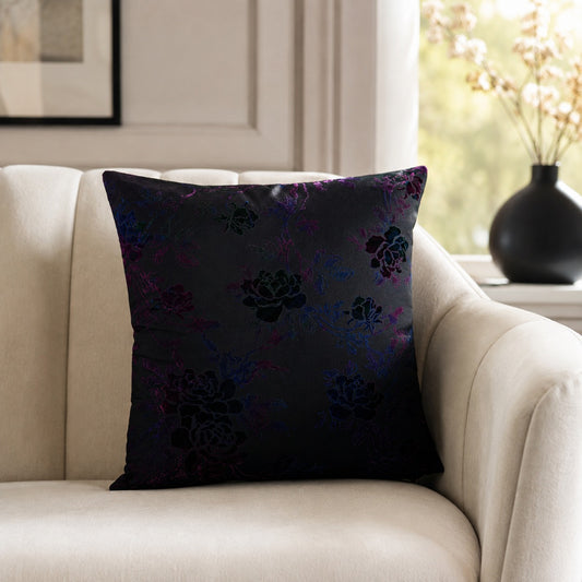 Dark purple decorative cushion with subtle floral pattern on a cream armchair
