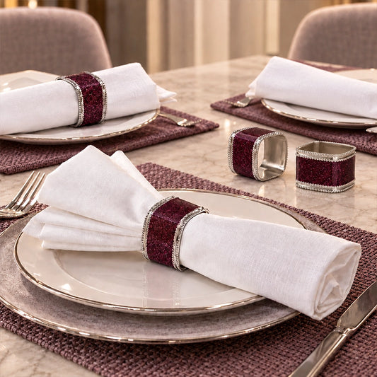 Purple napkin ring holding a white folded napkin beside a dark red table runner
