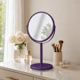 Purple swivel table mirror on vanity with makeup brushes