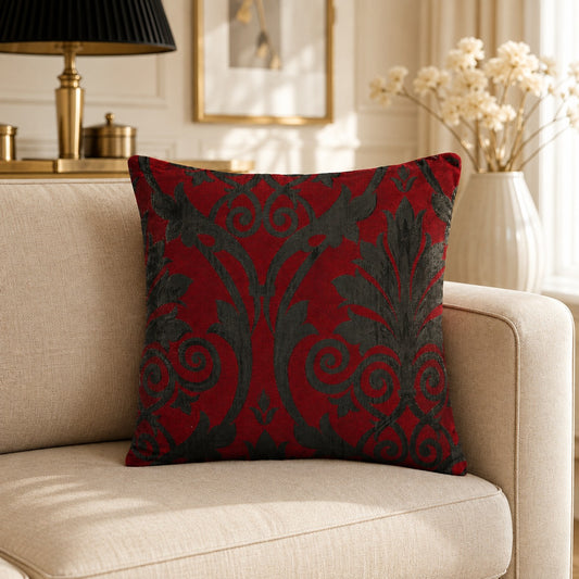 Red and dark grey decorative cushion with ornate damask pattern on a neutral armchair