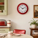 Red wall clock above dining table with red chair and home decor