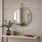 Round wall mirror with gold finish frame above bathroom vanity