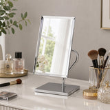 Silver rectangular table mirror on vanity with beauty accessories
